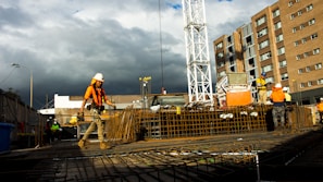 Drone shot of construction workers in safety gear actively working on a modern building site.