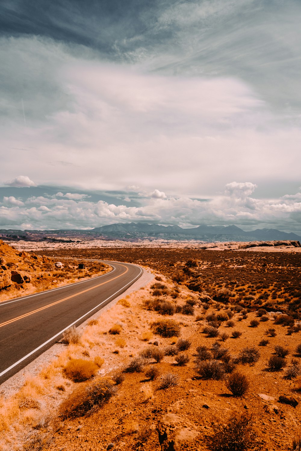 gray asphalt road under white clouds during daytime