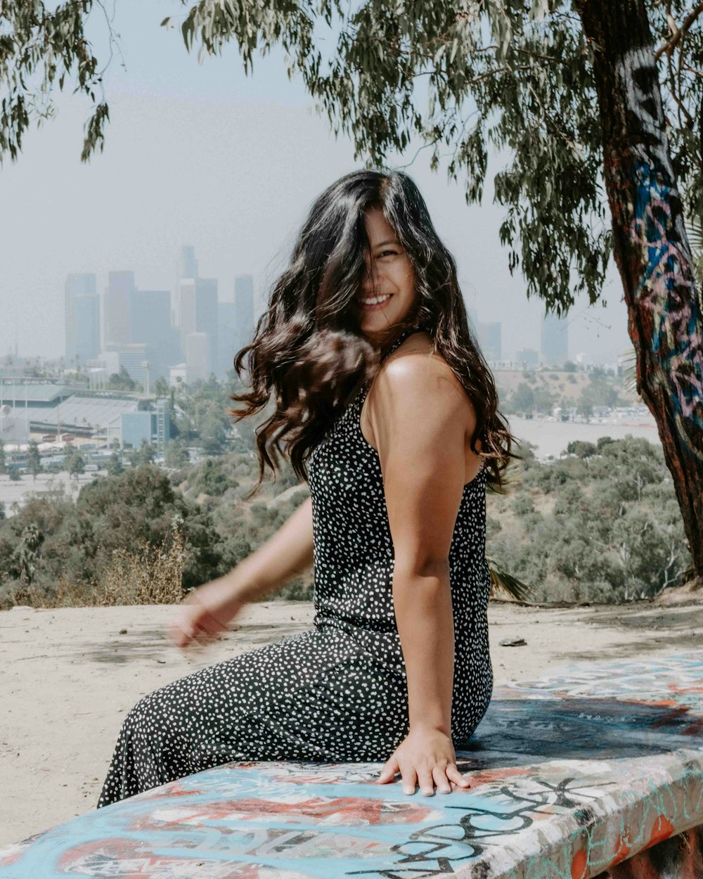 woman in black and white polka dot dress sitting on beach shore during daytime