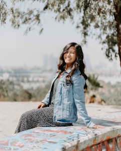 woman in blue denim jacket sitting on concrete bench during daytime