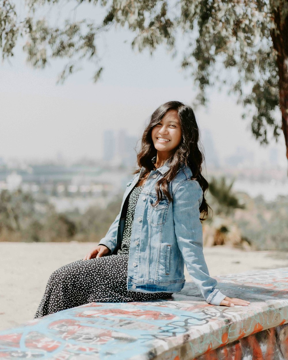 woman in blue denim jacket sitting on concrete bench during daytime