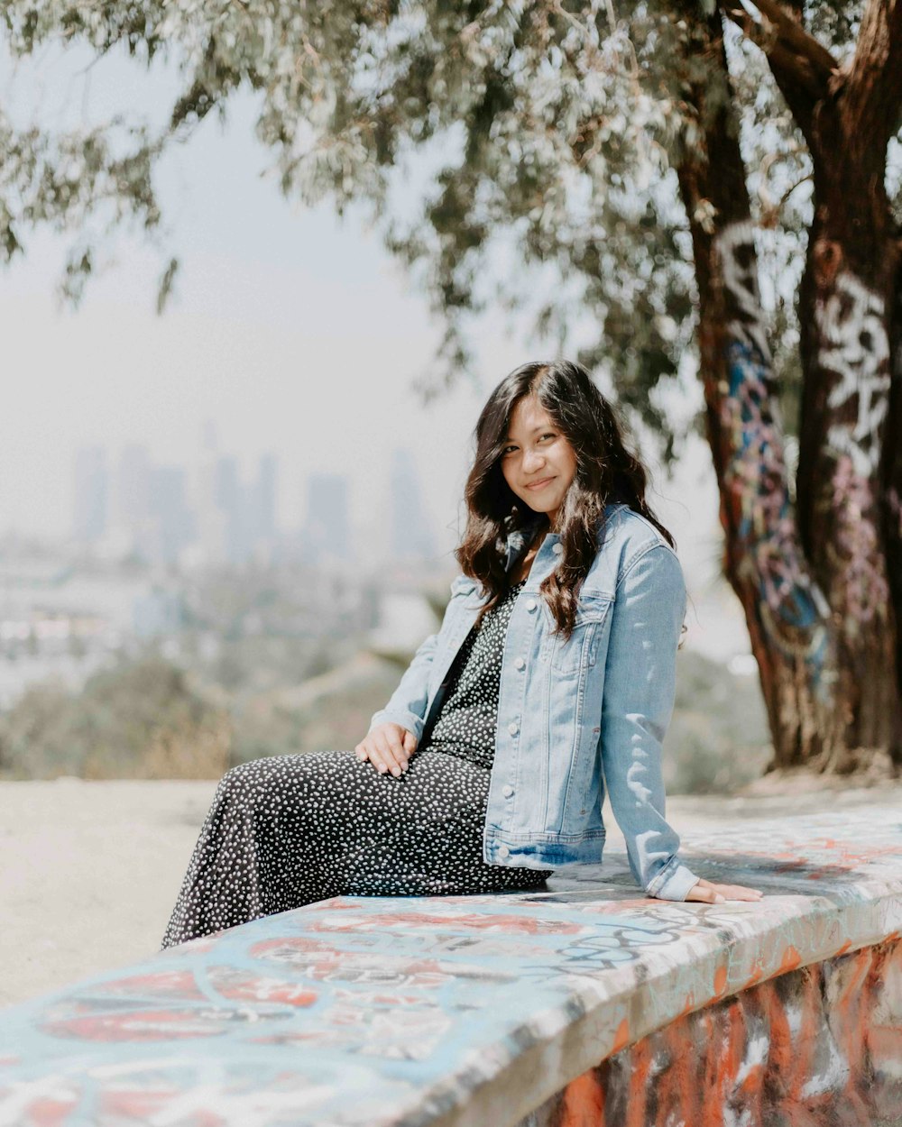 woman in blue denim jacket sitting on concrete bench during daytime