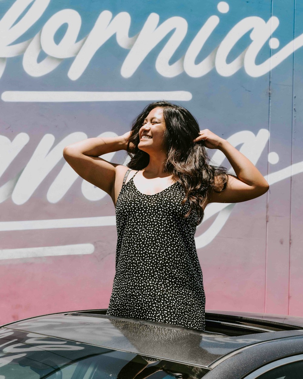 woman in black and white polka dot dress standing near wall