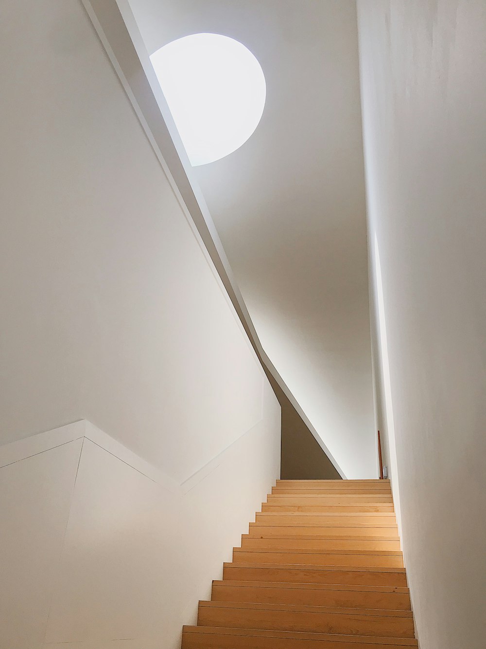 brown wooden staircase near white wall