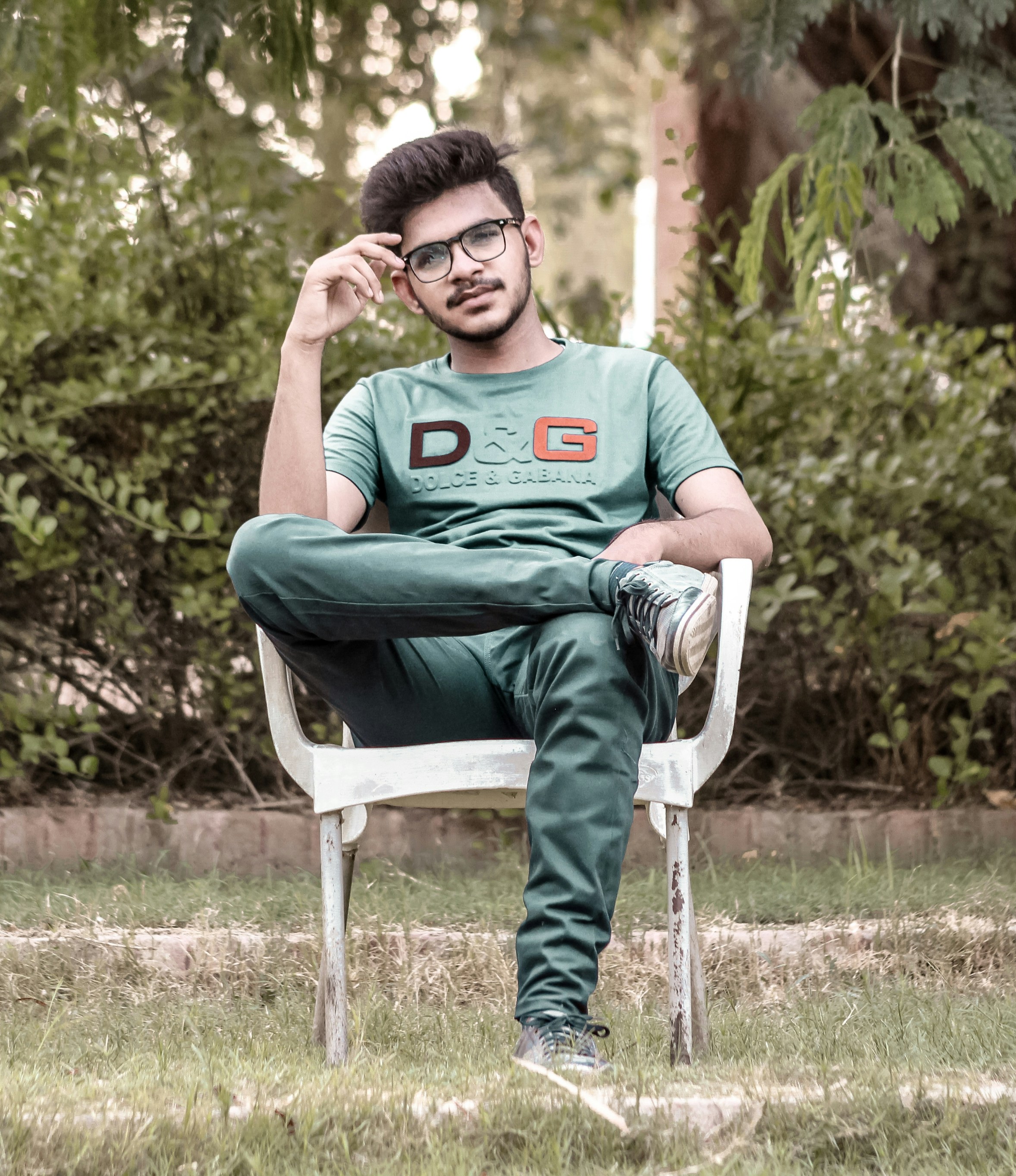 man in green crew neck t-shirt sitting on white plastic armchair
