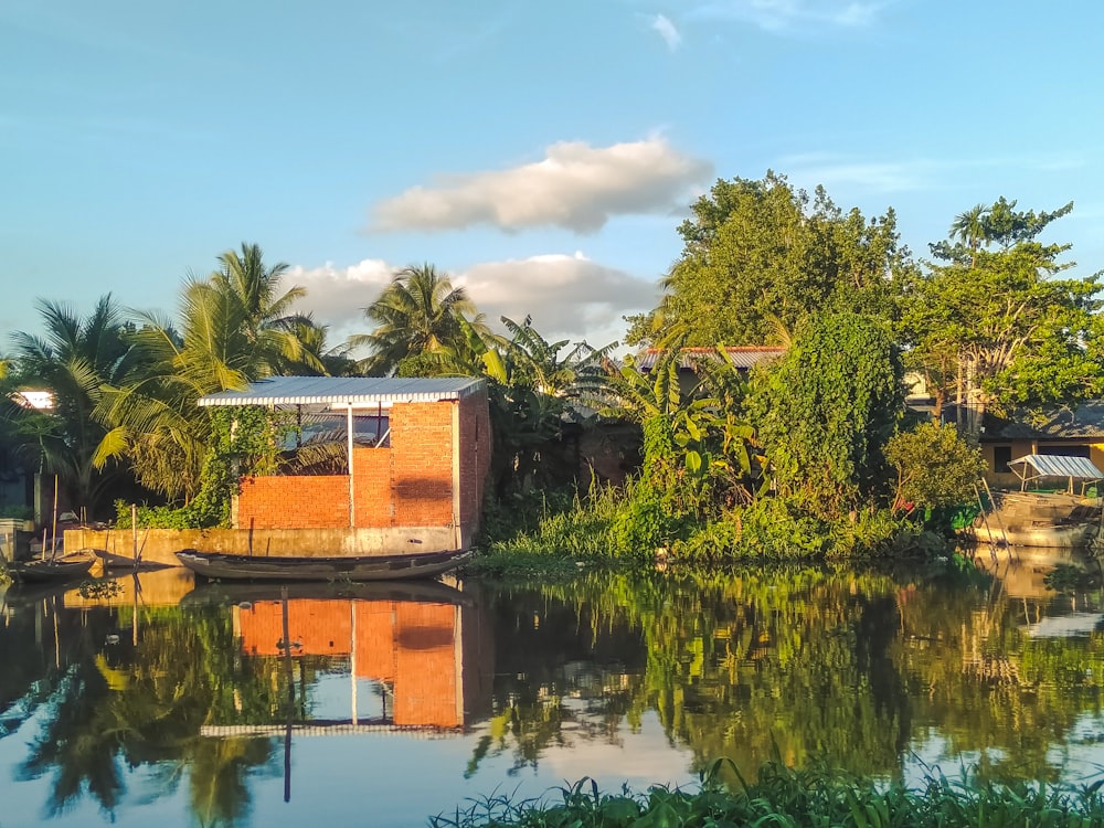 brown and white house near green trees and body of water during daytime