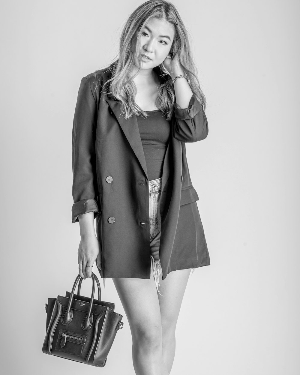 woman in coat holding black leather handbag