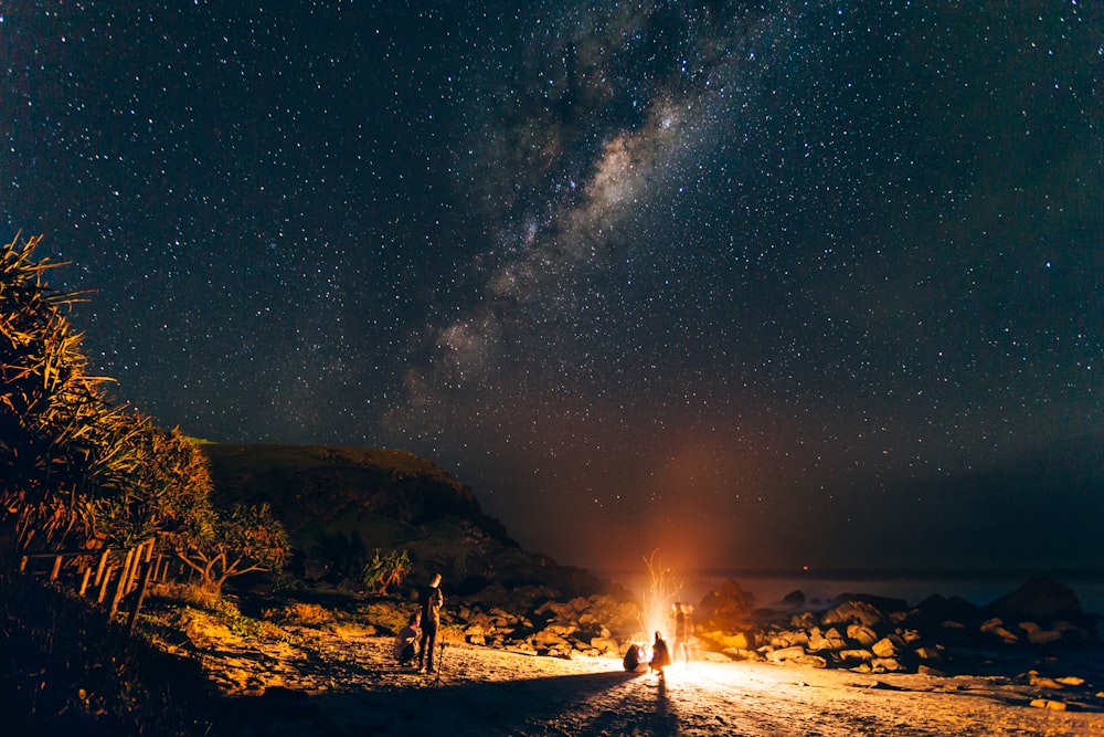 pessoa em pé na areia marrom sob a noite estrelada