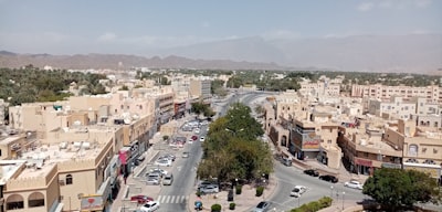 cars parked on parking lot near buildings during daytime oman zoom background