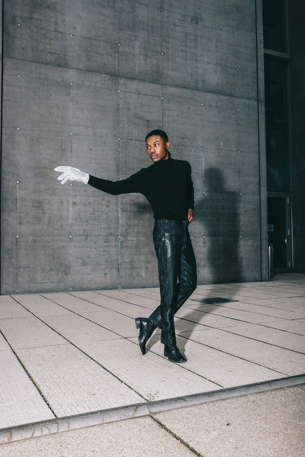 man in black long sleeve shirt and black pants standing on gray concrete floor