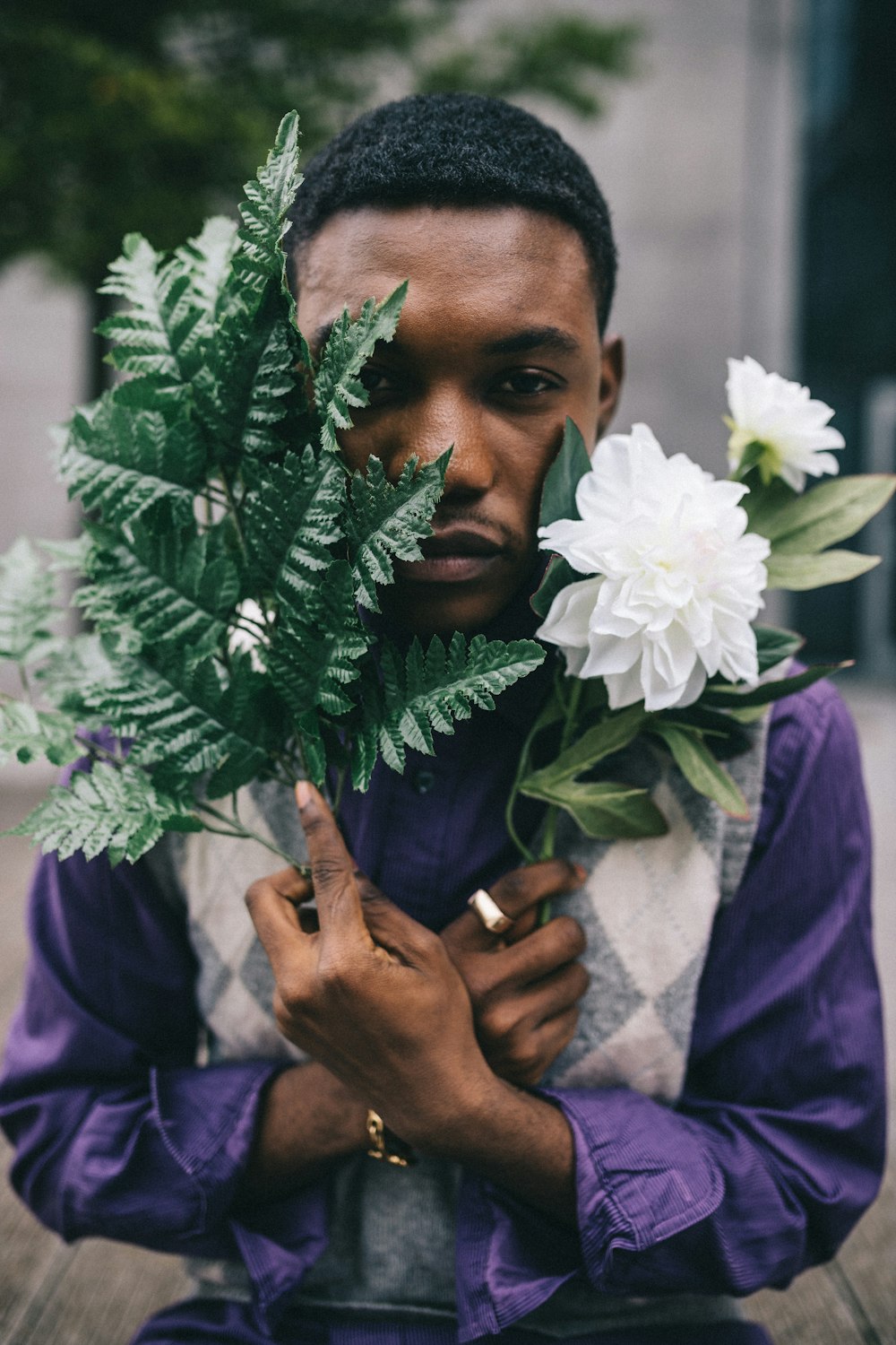 man in purple shirt holding white flower