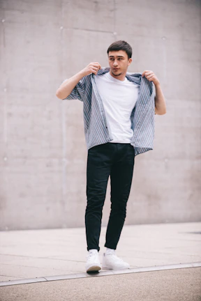 Young man wearing olive kingdom streetwear, standing confidently against a minimalist urban backdrop.
