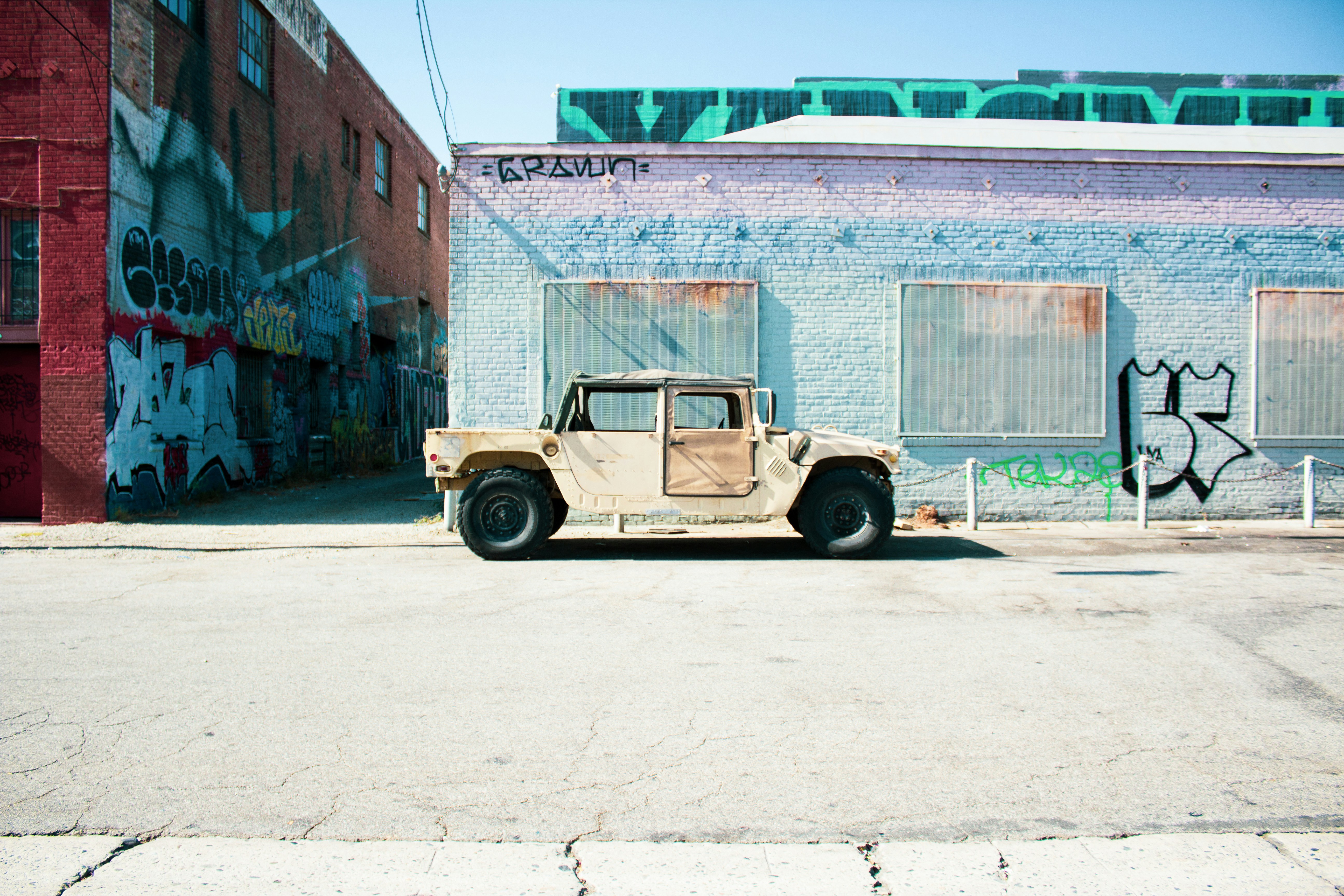 beige car parked beside concrete building during daytime, A hummer sits in the arts district