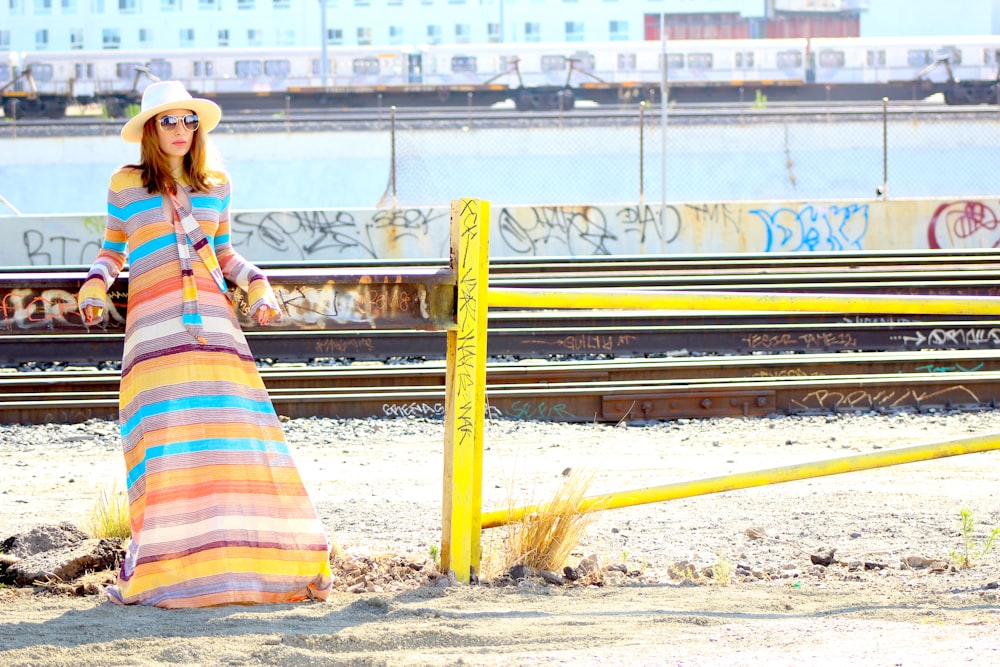 woman in red yellow and blue plaid dress shirt standing on train rail during daytime