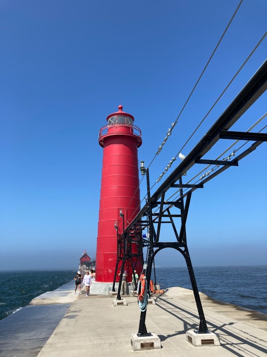 red and white lighthouse near body of water during daytime in Grand Haven State Park United States