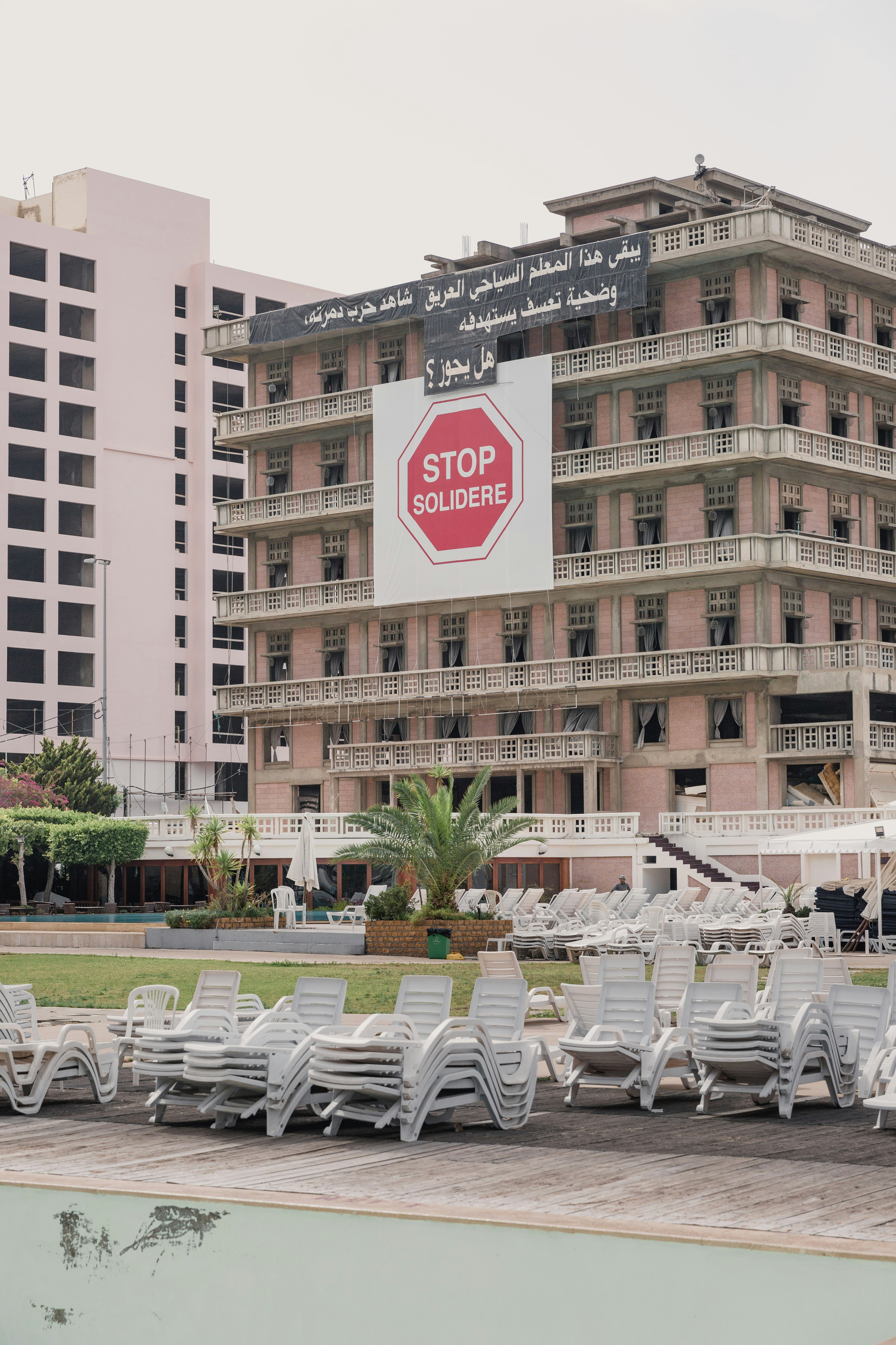 Chaises et tables blanches près d’un bâtiment en béton brun pendant la journée