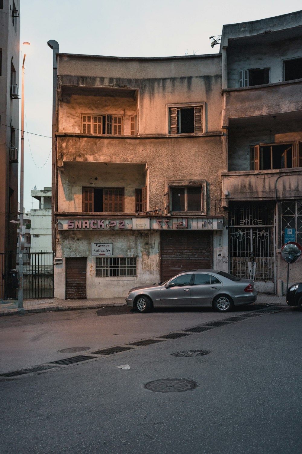 silver sedan parked beside brown concrete building during daytime