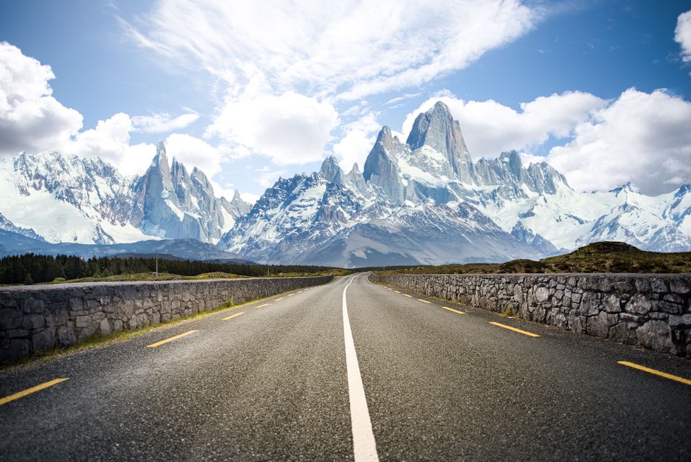 gray concrete road near mountain under white clouds during daytime