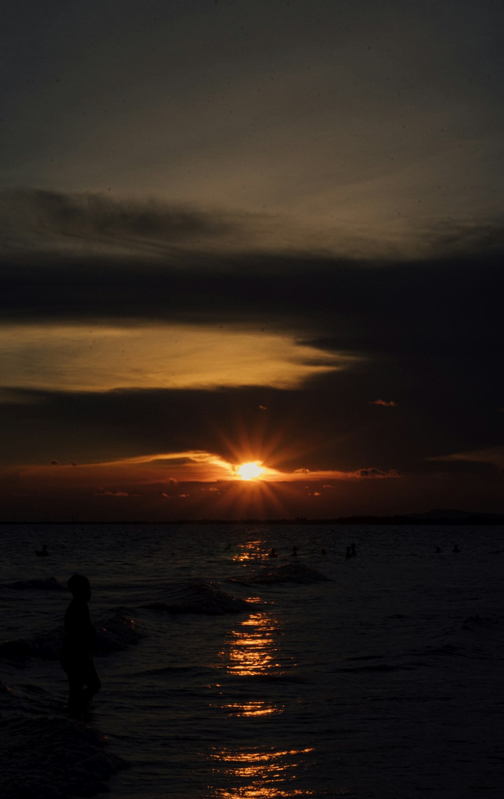 silhouette of person standing on beach during sunset