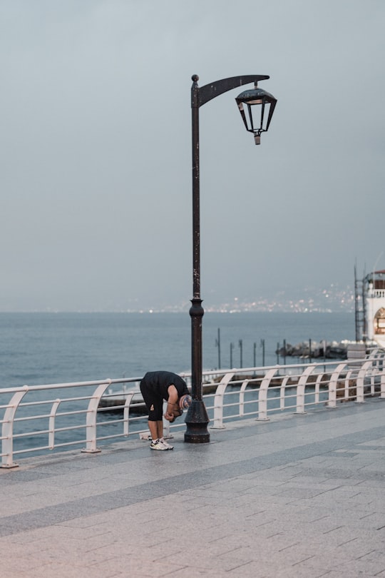 woman in black t-shirt and black shorts standing on gray concrete pavement near body of near near near near in Beirut Lebanon