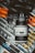 A camera with a distinctive lens is placed on a variety of stickers and decals from brands like Starbucks Coffee, Rimowa, and others. The camera's screen displays settings like ISO 1600 and F5.0. The design on the lens features an abstract pattern with lines and curves on a white background.