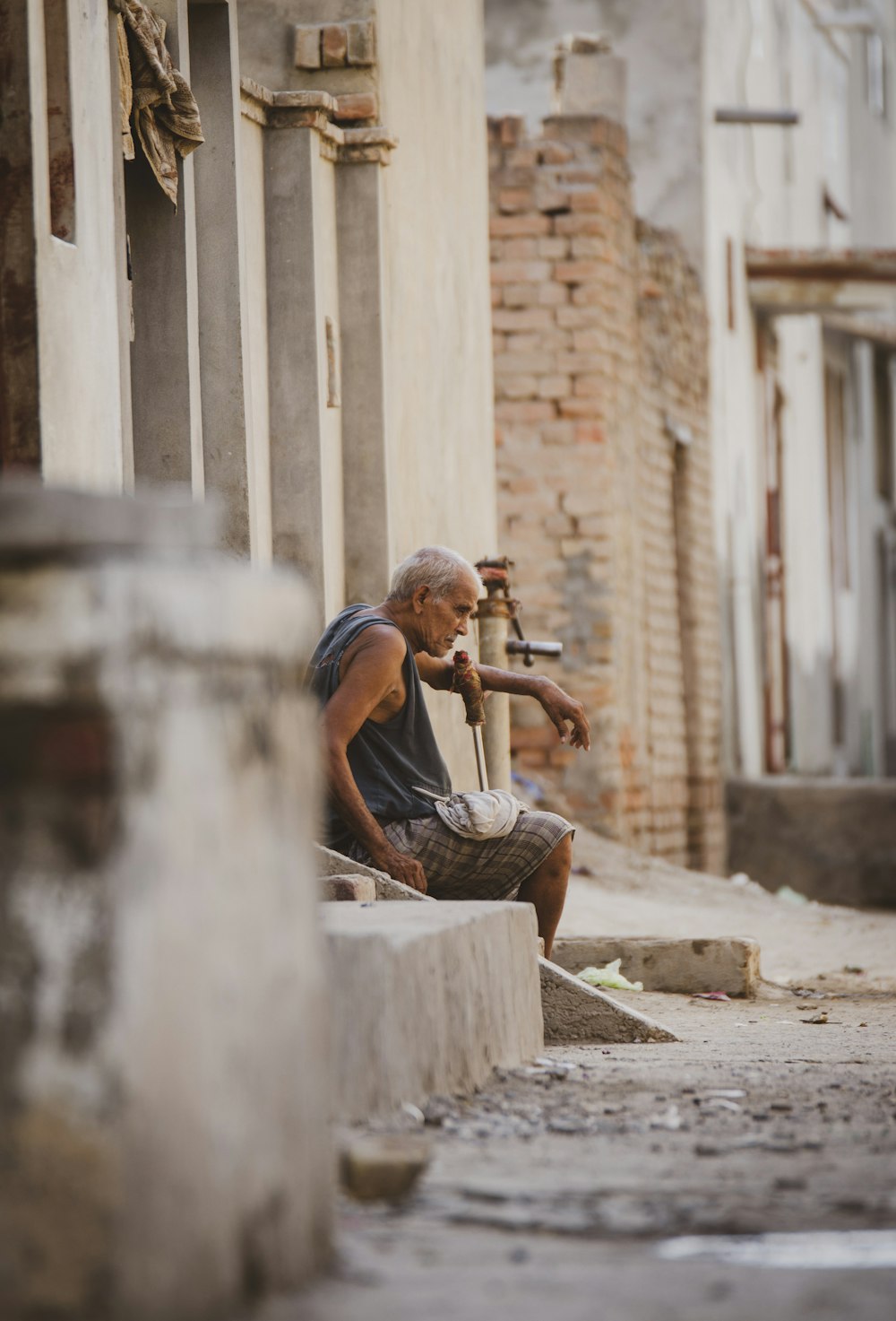 a man sitting on a curb with a pipe in his hand