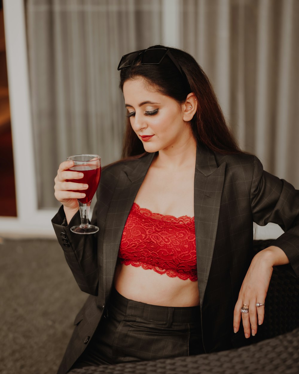 woman in red lace brassiere and black blazer holding clear drinking glass