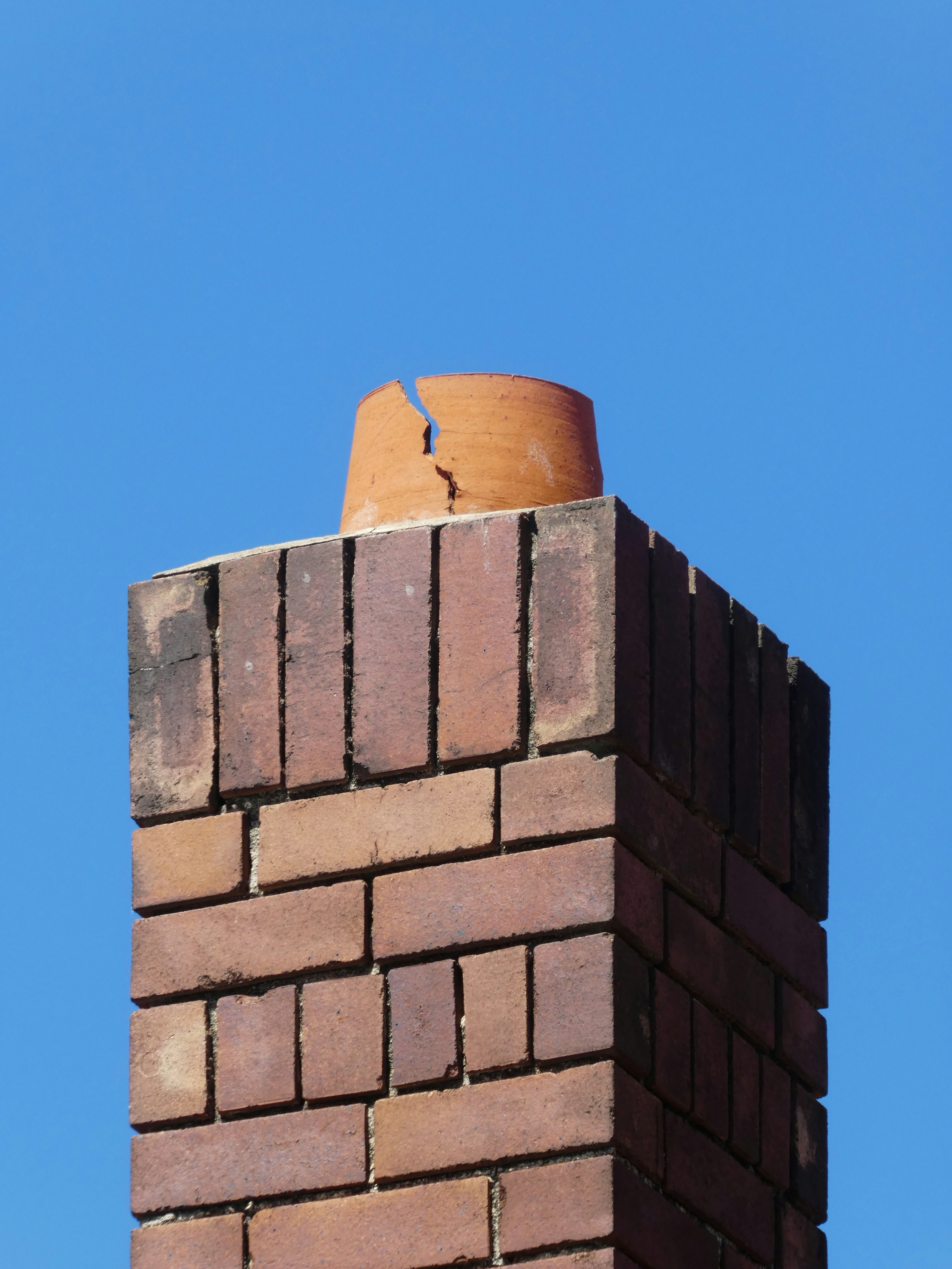 A chimney with a damaged crown and mortar joints
