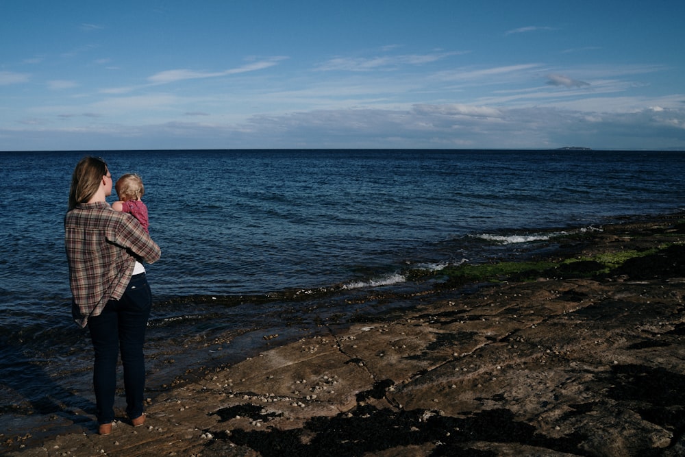 woman in black and white long sleeve shirt standing on seashore during daytime