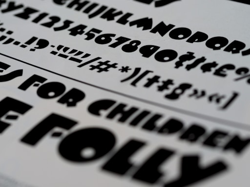 A selection of bold, black typography on a white paper background, featuring a variety of fonts and characters. These include uppercase and lowercase letters, numbers, and symbols.