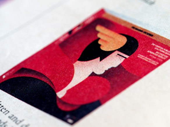 An abstract illustration featuring a stylized human face in profile, characterized by bold geometric shapes and a predominantly red and black color scheme. The image has an art deco influence, with distinct features such as a wing-like shape on the head. The composition is set on a textured surface, giving it a printed appearance.