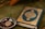 A Quran with an ornate cover is placed on a green fabric. Beside it, a small metallic bowl contains prayer beads and a clay tablet, both typically used in Islamic rituals.