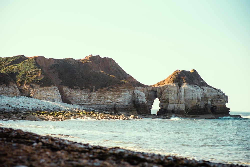 brown rocky mountain beside sea during daytime