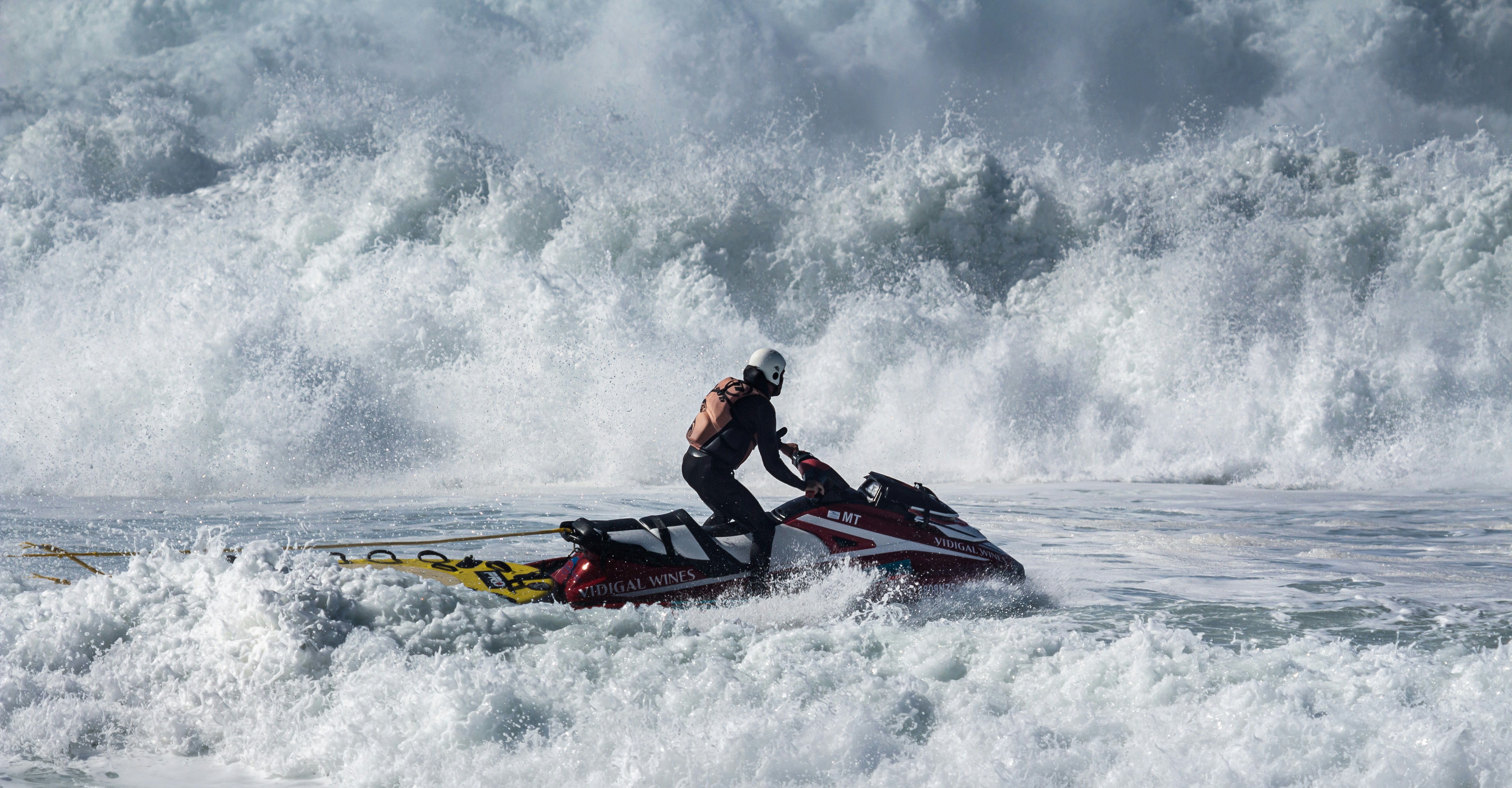 2 men riding on red and black kayak on sea during daytime, Brave jetski driver