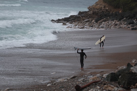 2 person holding surfboard walking on seashore during daytime in Guéthary France