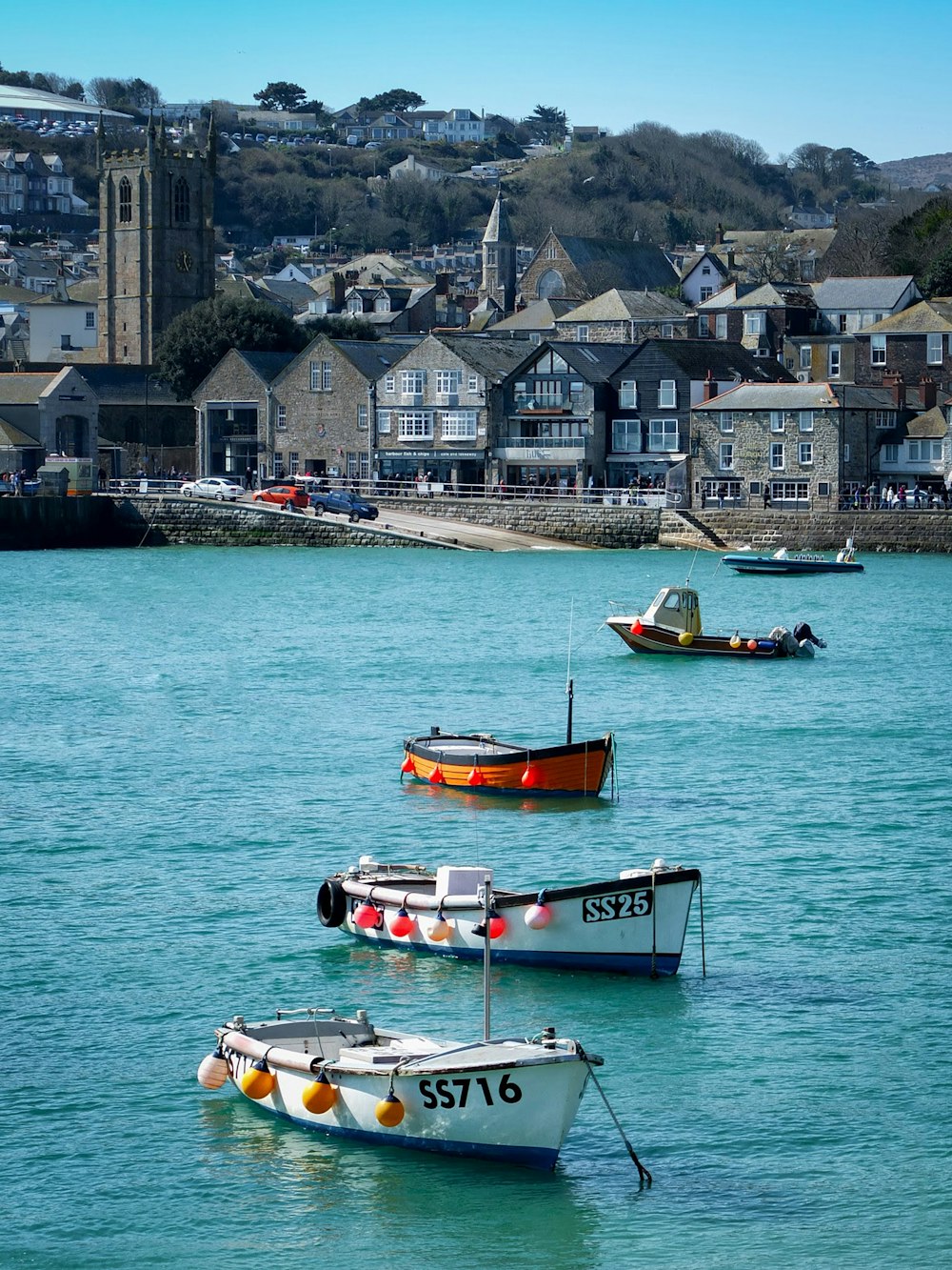 white and red boat on sea near houses during daytime