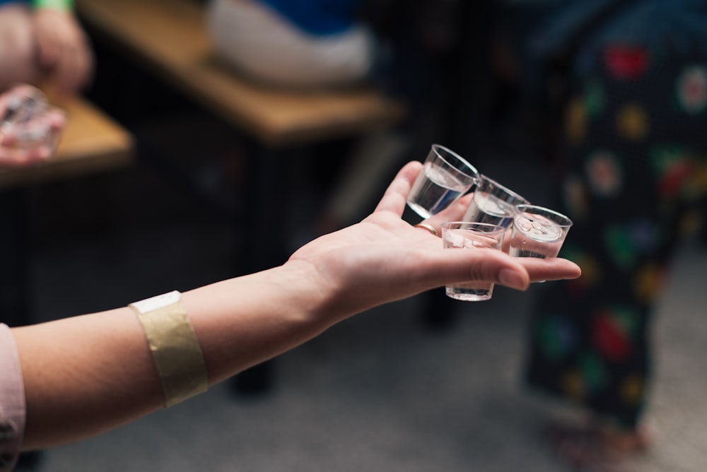 person holding clear glass bottle