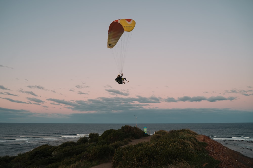 person in yellow parachute over the sea during daytime