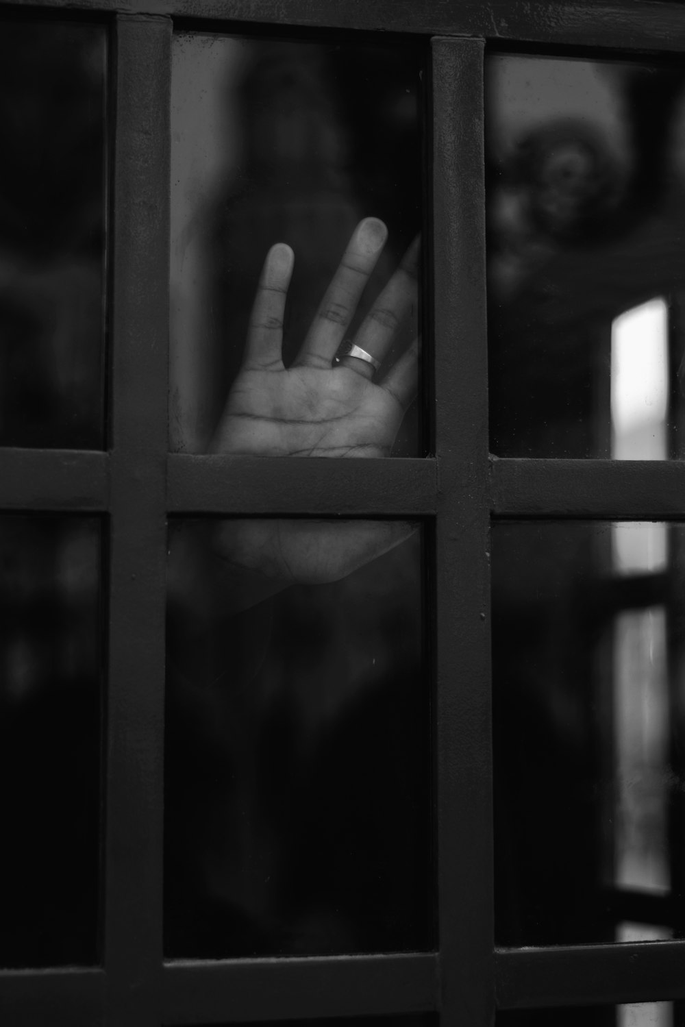 grayscale photo of persons hand on window