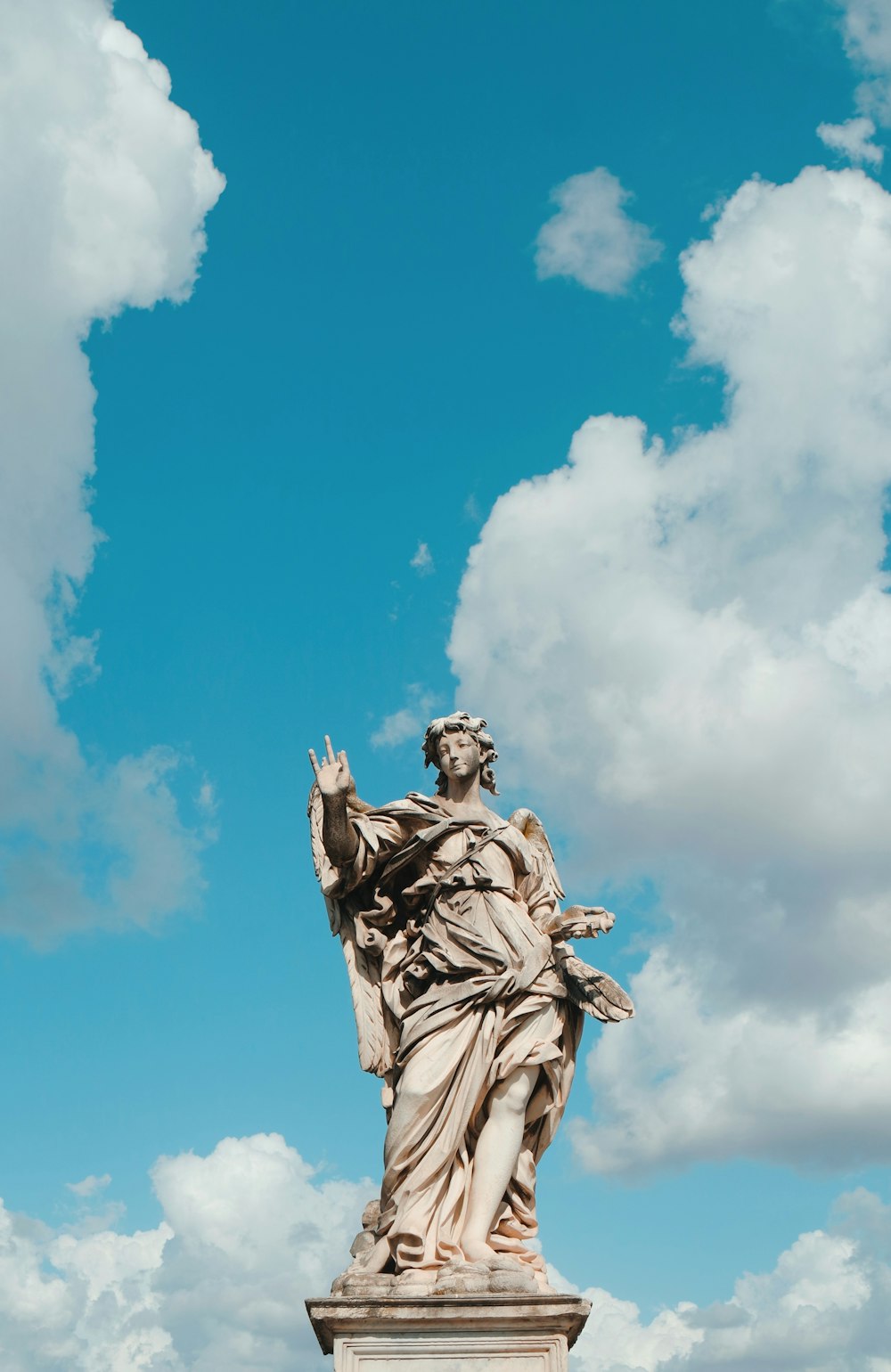 hombre con túnica estatua bajo un cielo azul durante el día
