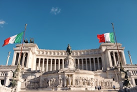 white concrete building with statue under blue sky during daytime