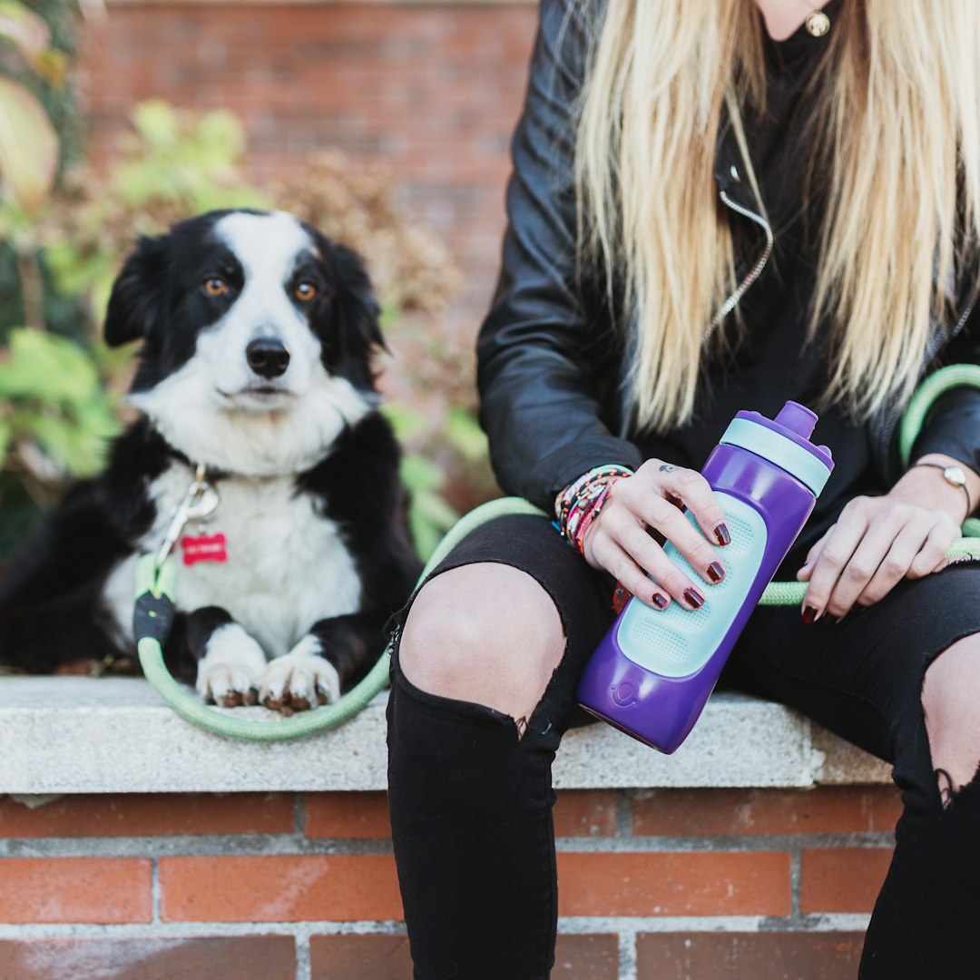 woman in black jacket and black leggings sitting on brown concrete bench with purple and white