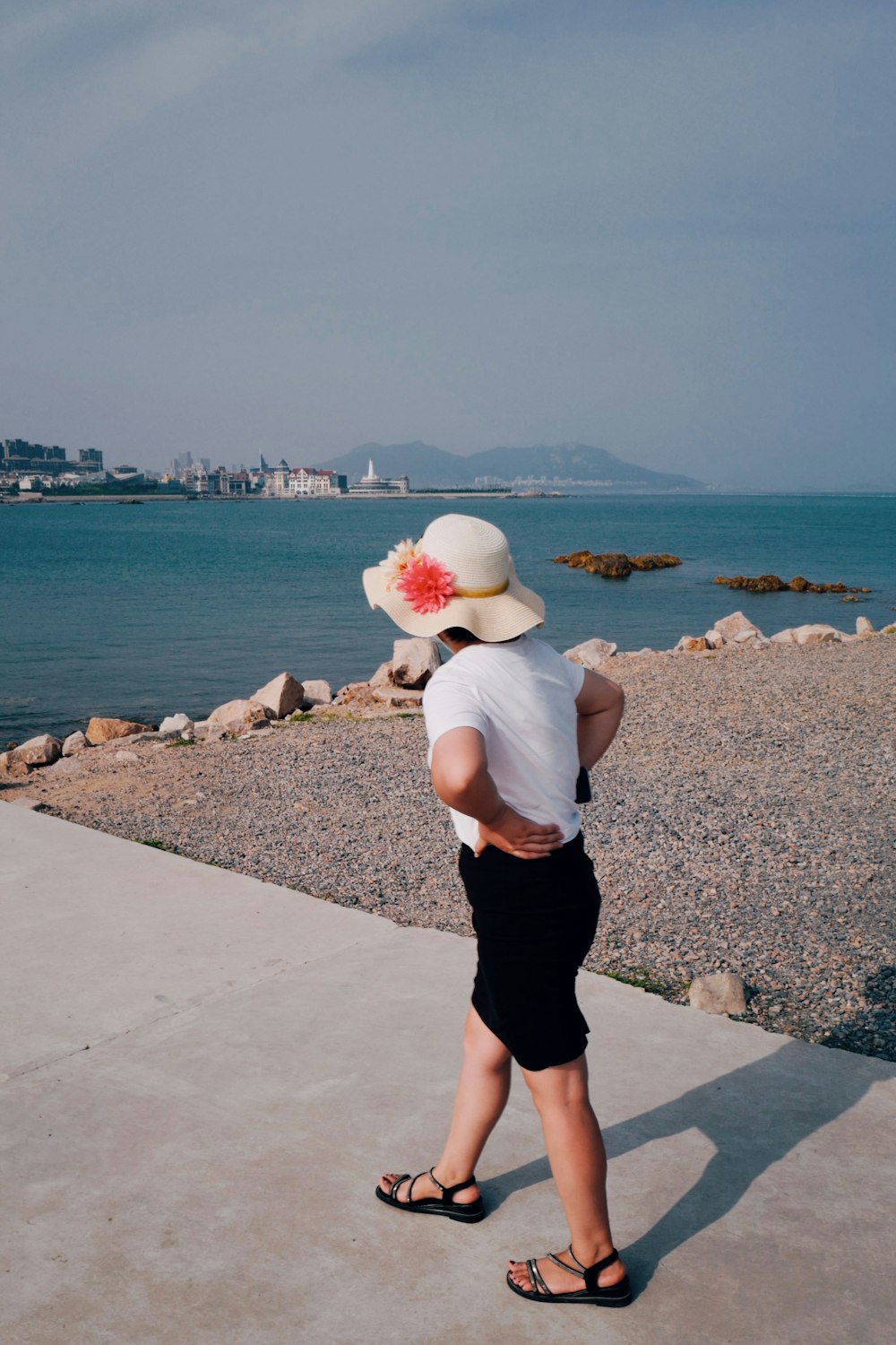 woman in white shirt and black skirt standing on gray concrete dock during daytime