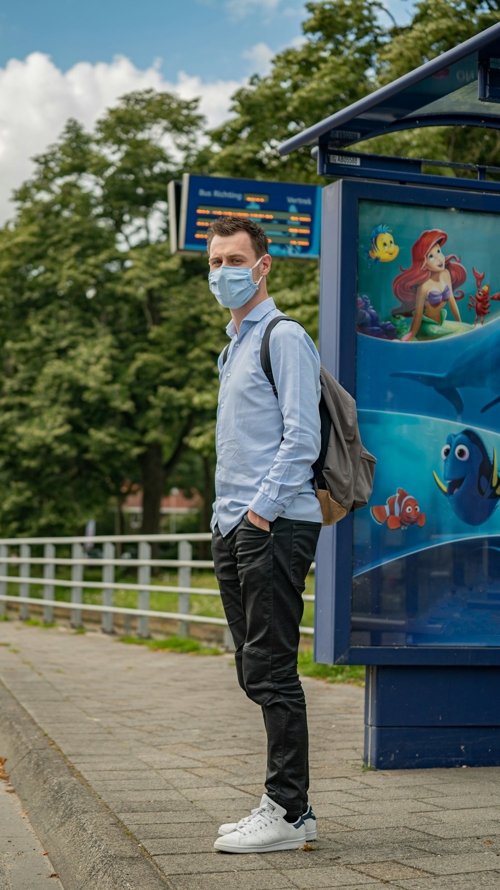 man in white dress shirt and blue denim jeans standing beside blue and white wooden board