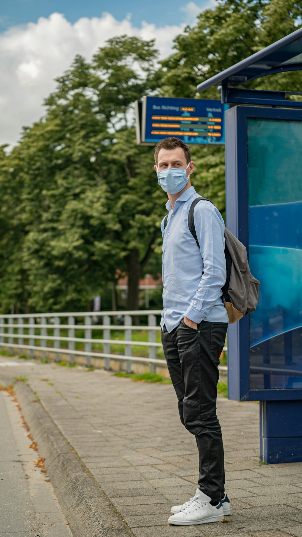 uomo in camicia bianca e gilet nero in piedi vicino al muro blu e bianco durante il giorno