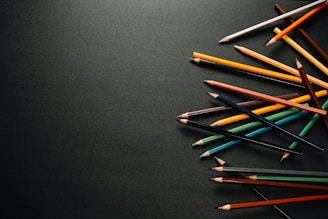 A close-up of colored pencils scattered next to a half-colored funny skateboarding comic page.