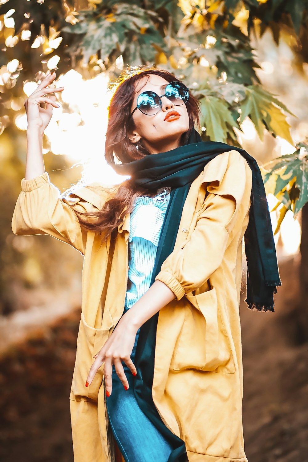 woman in brown coat wearing blue scarf and black sunglasses