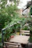 A modern small garden dining setup with fold-flat chairs and a wooden table surrounded by greenery.