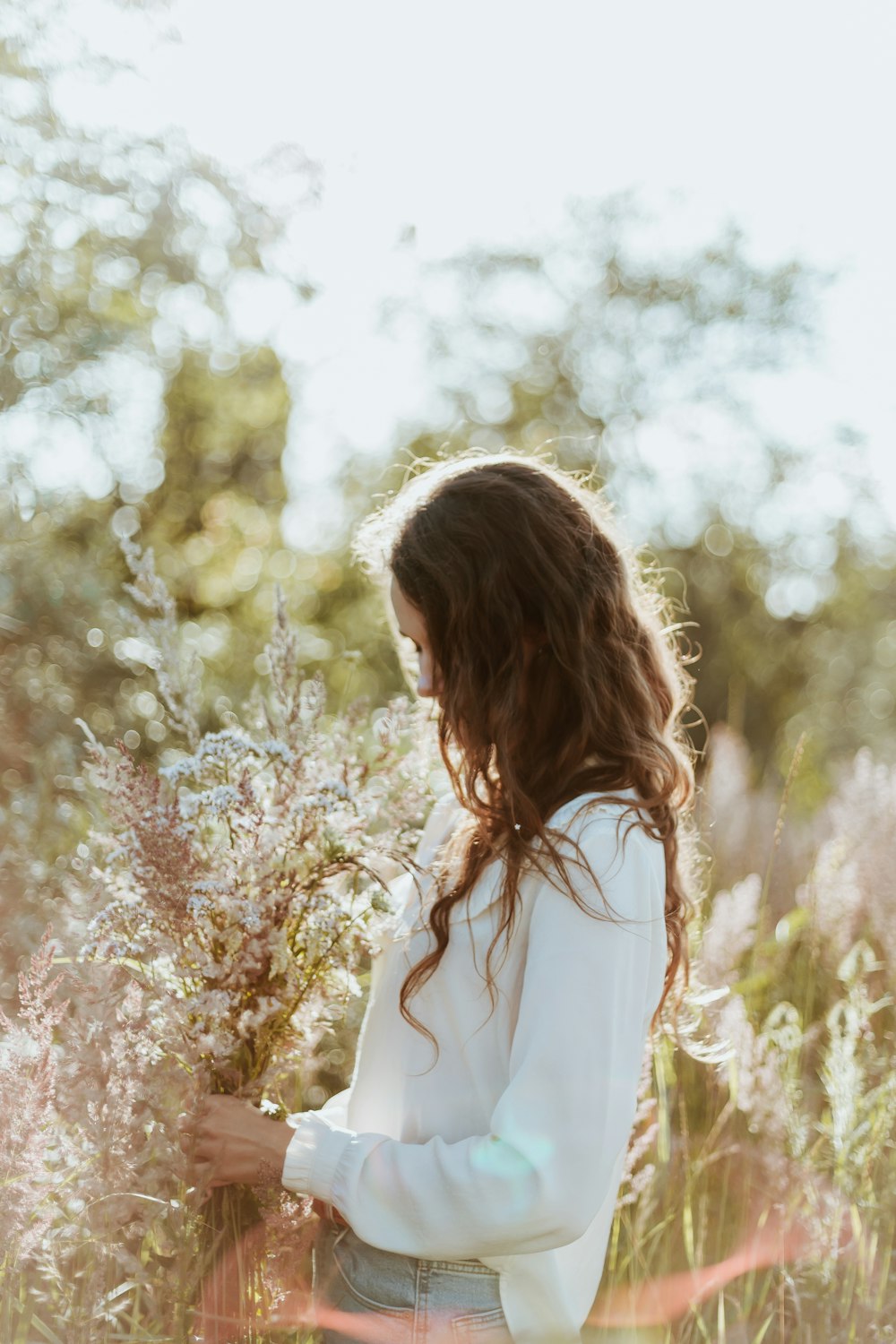 woman in white long sleeve shirt standing near white flower trees during daytime