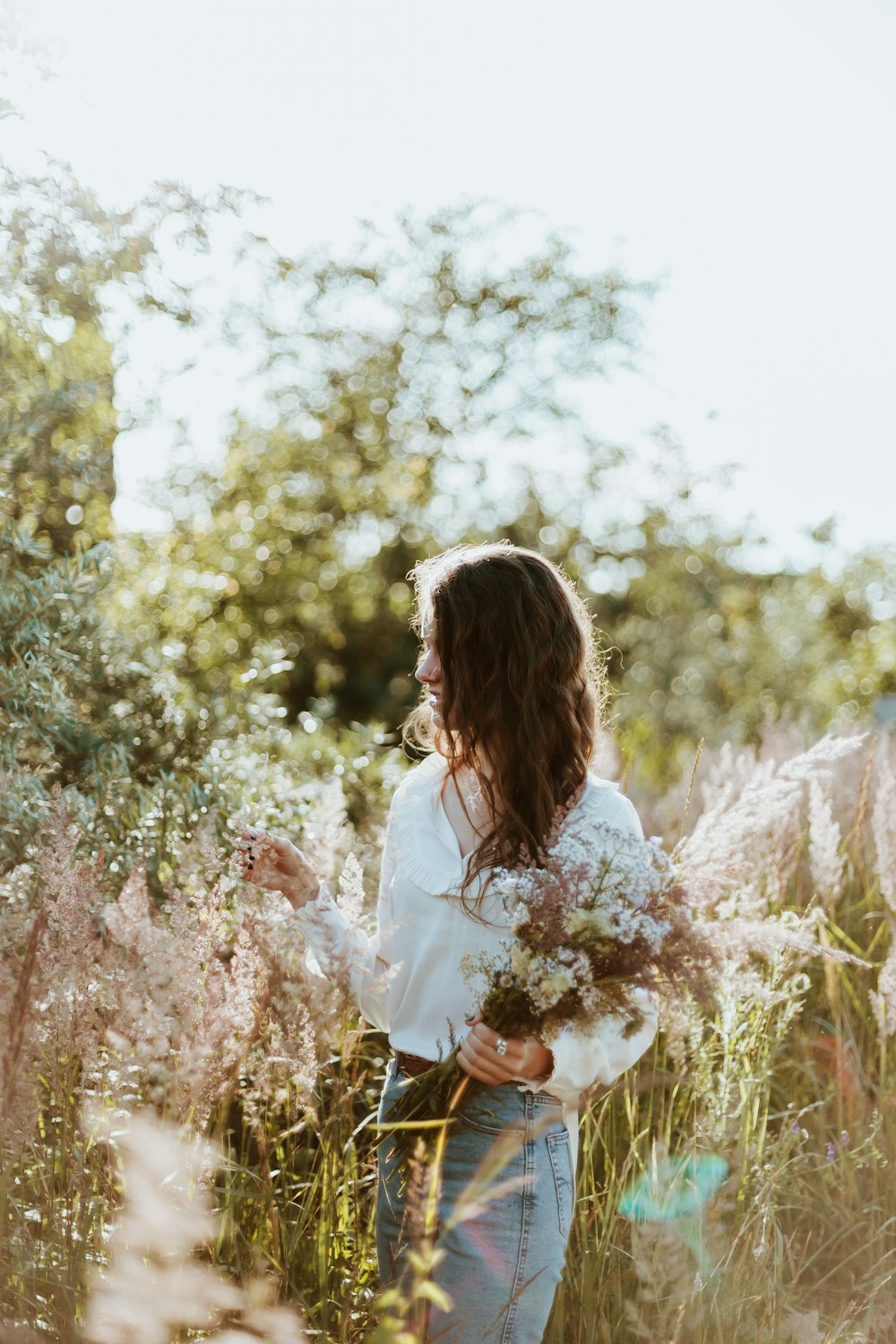 Woman in white long sleeve shirt standing on brown grass field during ...